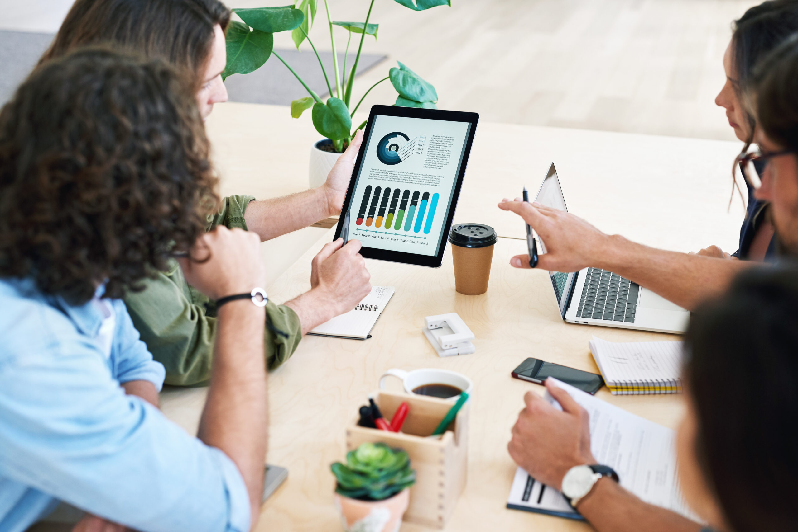 Business people using digital tablet computer discussing financial graph data on mobile touchscreen.
